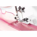 Close-up of a sewing machine stitching pink fabric with precision.